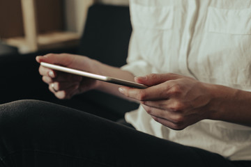 Mockup image of a woman sitting and holding white tablet pc with blank desktop screen