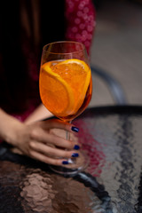 Hand with glass of  Aperol spritz cocktail in the bar