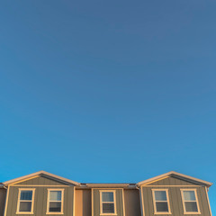 Fototapeta na wymiar Square frame Upper storey of townhomes viewed from below against blue sky on a sunny day