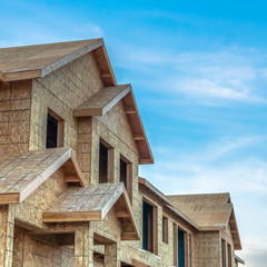 Square Construction of townhouses viewed against blue sky and clouds on a sunny day