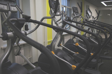 Treadmills and bikes in a fitness hall. Fitness club with row of treadmills for fitness cardio training in evening backlight. Healthy lifestyle concept.selective focus