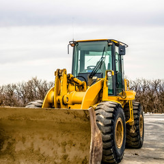 Square Focus on a yellow bulldozer with dirty bucket and wheels at a construction site