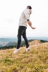 Fototapeta premium man with backpack happy jumping on the peak on the mount