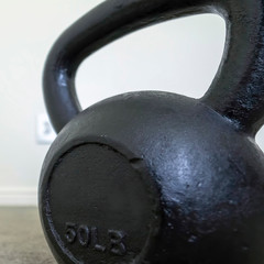 Square Focus on a heavy kettlebell inside a room with carpeted floor and white wall