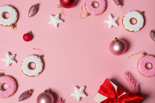 paper pink background with Christmas decoration balls, donuts, gift and stars.   flat lay, top view. Christmas card conception. 