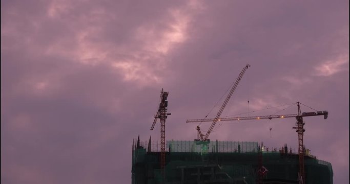 Footage timelapse 4k. Time lapse building construction site working. Stock video timelapse construction buildings. Construction process of skyscraper with cranes on the roof and clouds on a sunrise