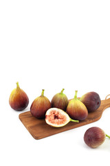 fig fruits and one cut figs on wooden cutting board 