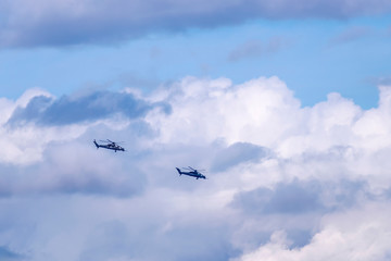 Fototapeta na wymiar Two military helicopters flying against a beautiful sky with clouds