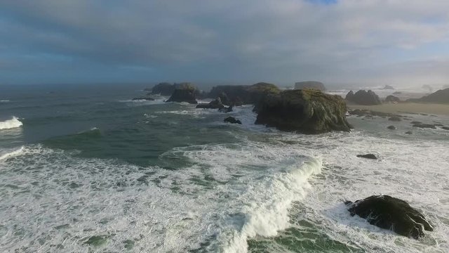 The waves crach into the rugged, rocky landscape of the ocean in this high aerial drone shot