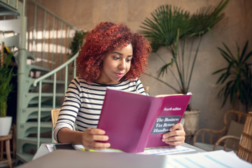 Promising young businesswoman reading business book attentively