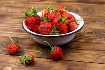 Fresh ripe strawberry in white bowl on a wooden table