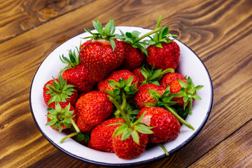 Fresh ripe strawberry in white bowl on a wooden table