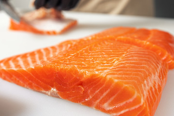 Salmon fillet on a white Board cut into large pieces. Close up.