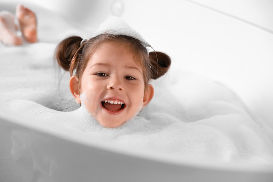 Cute little girl taking bubble bath at home