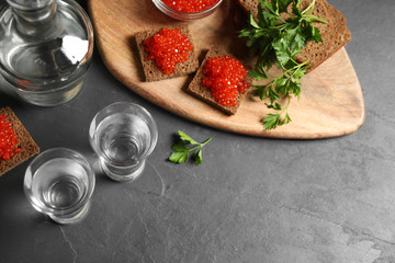 Cold Russian vodka and sandwiches with red caviar on black table, above view