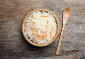 Tasty fermented cabbage on wooden table, flat lay