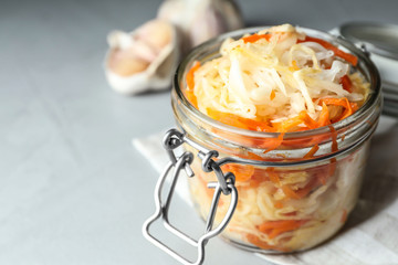 Tasty fermented cabbage with carrot on light grey table, closeup