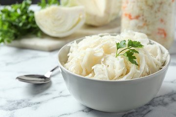 Tasty fermented cabbage on white marble table, closeup
