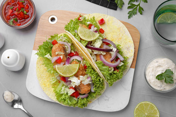 Delicious fish tacos served on light grey table, flat lay