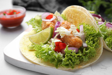 Delicious fish tacos served on light grey table, closeup