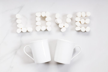 White ceramic cup and love-shaped marshmallows on white background