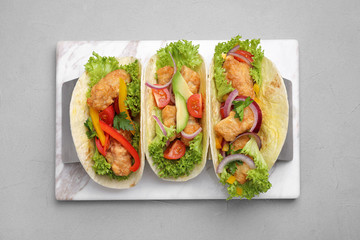 Delicious fish tacos served on grey table, top view