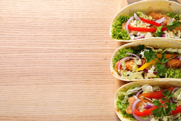 Delicious fish tacos served on wooden table, top view with space for text