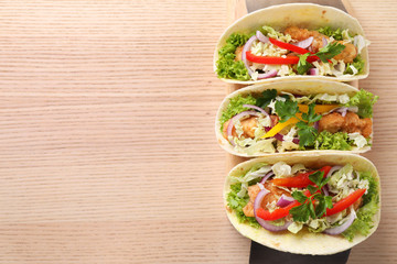 Delicious fish tacos served on wooden table, top view with space for text
