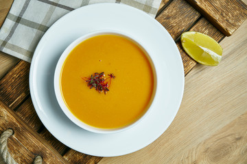 Lentil cream soup with a slice of lemon on a wooden tray in a white bowl. Healthy and vegan food. Go green. Close up