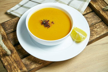 Lentil cream soup with a slice of lemon on a wooden tray in a white bowl. Healthy and vegan food. Go green. Close up