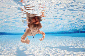 Happy young boy swim and dive underwater, kid breast stroke with fun in pool. Active healthy lifestyle, water sport activity and lessonson summer family vacation with child.