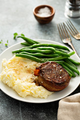 Traditional dinner meal with a bacon wrapped steak, green beans and mashed potatoes