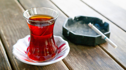 black turkish tea and burning cigarette on ashtray on wooden table