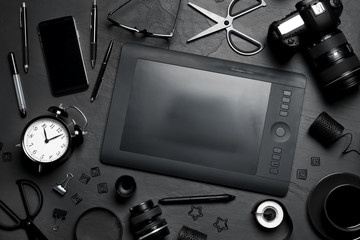 Flat lay composition with graphic drawing tablet and different office items on black table....