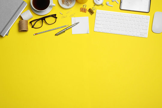 Flat lay composition with computer accessories and different office items on yellow background, space for text. Designer's workplace