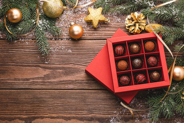 Chocolate candies in a red craft box wooden Christmas background fir branches of a New Year's toy....