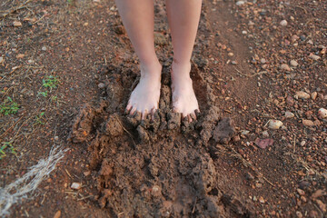 Kid bare foot with muddy feet on the rural road.