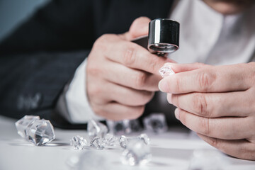 Businessman jeweler during the evaluation of jewels with magnifier. Jeweler looking at diamonds or...