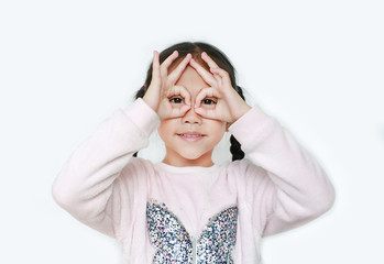 Kid with hands glasses in front of her eyes isolated on white background. Little asian girl looking through imaginary binocular.