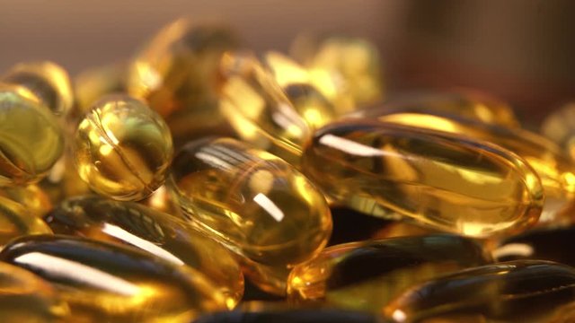 Omega 3 gold fish oil capsules, rotation background, macro. Capsule gold oil gel supplement rotating movement, Omega 3 Fish Oil, Healthcare pharmacy medical concept.