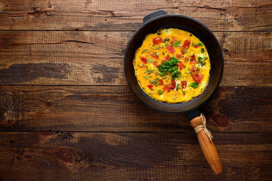omelet with old cast iron pan on wooden background with copy space