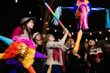 Mexican Posada friends breaking a Piñata celebrating Christmas Mexico
