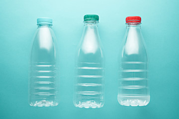 Three liter Plastic bottles of different shapes with lids on turquoise, neo mint background