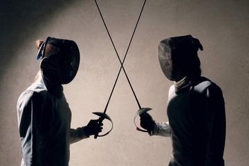 Fencer woman with fencing sword. Fencers duel concept.