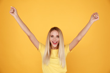 Woman in a winner pose in the yellow background