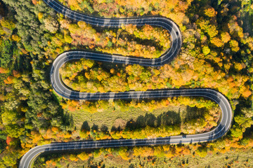 Beautiful aerial landscape of mountain forest road. Aerial view of curvy road in beautiful autumn forest
