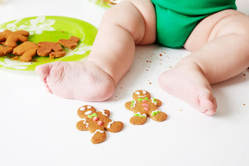 Handmade Gingerbread cookies for Christmas on white tabke  near  baby feet. Festive, sweet pastry, delicious biscuits. Home celebration, decoration concept