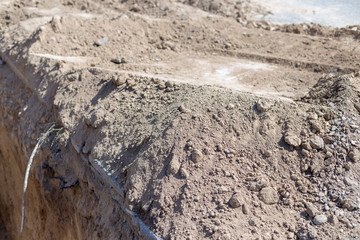 Laying pipelines of hot and cold water. Gas pipes are dug out by a tractor. Pit for urban communications. Excavations. Preparing for the construction of a house for residents