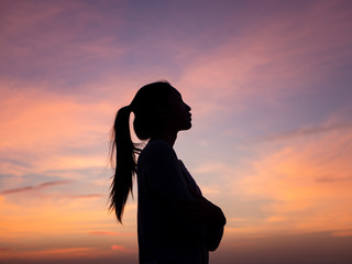Silhouette of young beautiful woman in  coat, posing at sunset, side view. Looking at right, copy space.