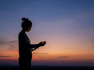Fototapeta premium Silhouette of young beautiful woman in coat, posing at sunset, side view. Looking at right, copy space.
